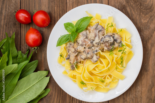 Fettuccine pasta in a creamy sauce with mushrooms on  plate   wooden table. Horizontal top view. Close-up photo