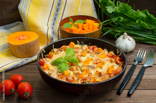 Casserole with chicken and pumpkin in a pan. Wooden rustic background. Close-up