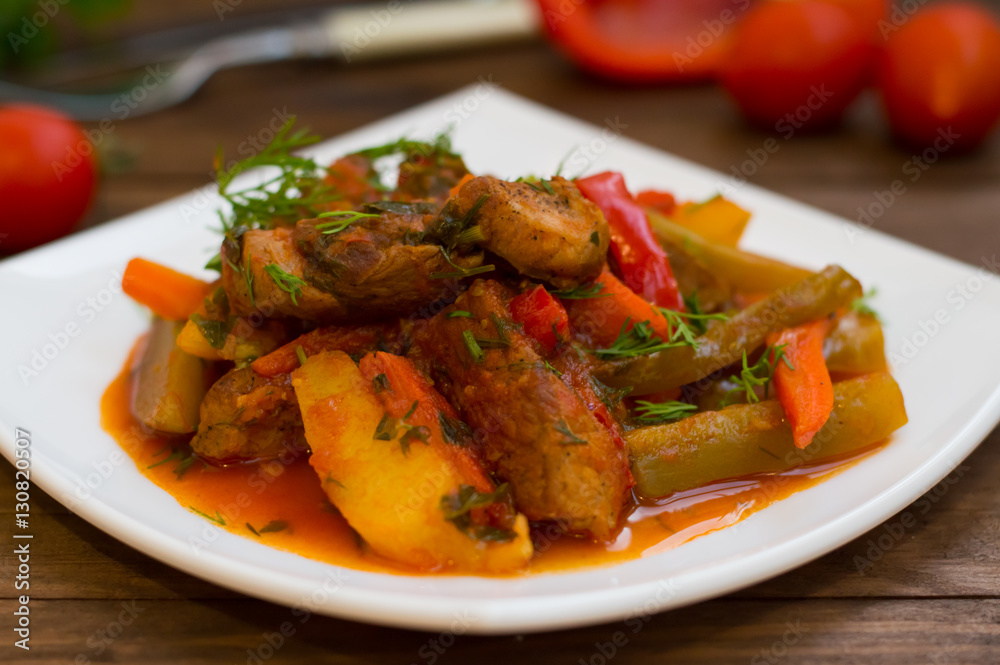 Stew with potatoes, carrots, pickles, tomatoes and hot peppers. Azu by Tartarian on a white square plate. Wooden rustic background. Top view. Close-up Stew with potatoes, carrots, pickles, tomatoes and hot peppers. Azu by Tartarian on a white square plate. Wooden rustic background. Top view. Close-up