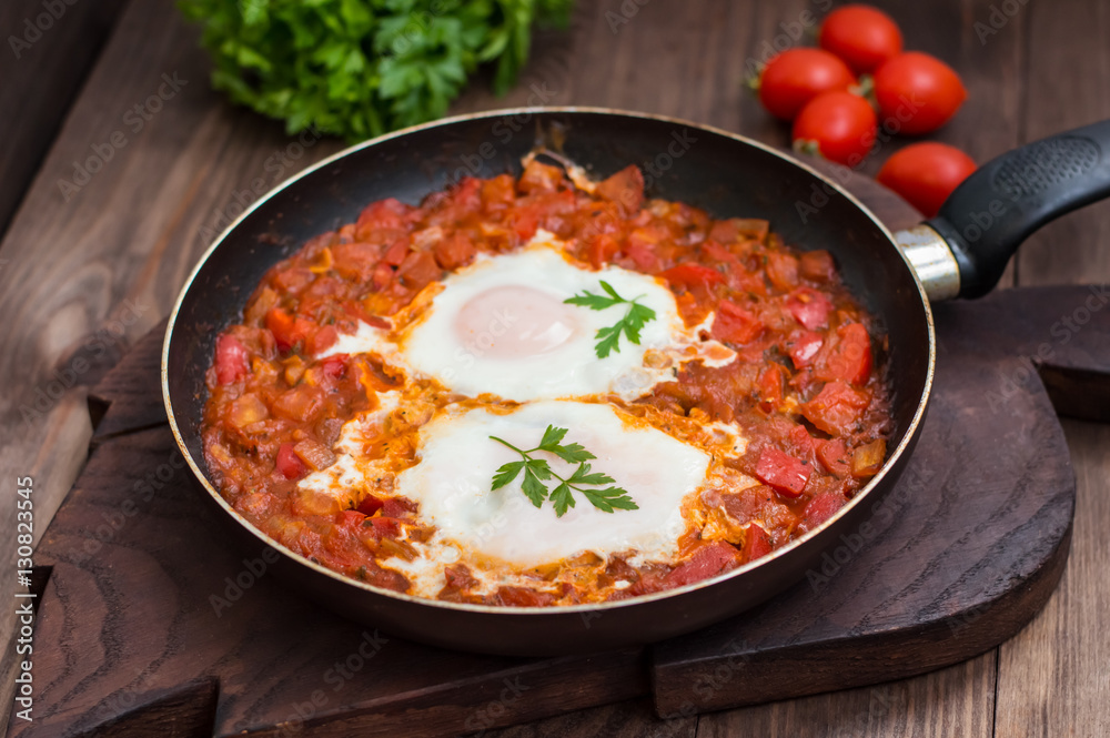 Shakshuka in a frying pan. Traditional Jewish dish. Wooden table. Close-up