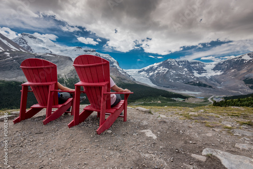 Behind View of Two People Sitting in Red Chairs photo