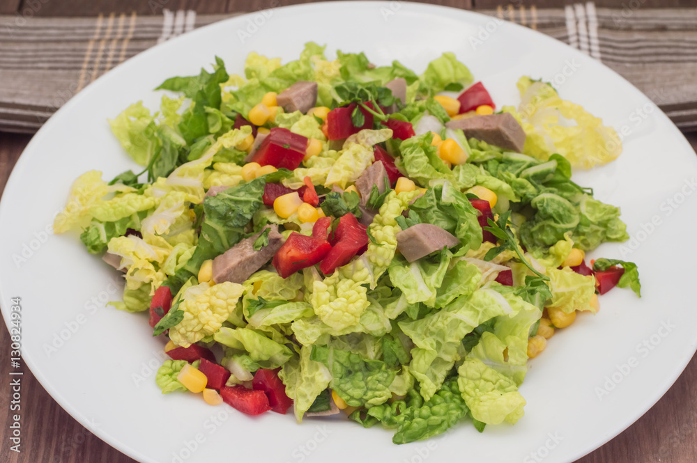 Salad from beef tongue, Chinese cabbage, peppers, corn, parsley and basil. Wooden background. Top view Salad from beef tongue, Chinese cabbage, peppers, corn, parsley and basil. Wooden background. Top view