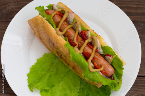 Hot dog with grilevskoy sausage, lettuce, radish and mustard, on a wooden background. Top view photo