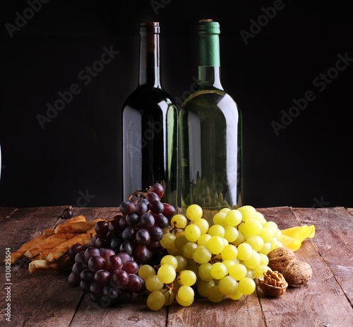Bottle of white wine, grape and corks on wooden table 
