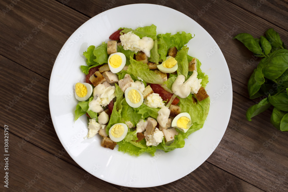 Salad with grilled chicken, lettuce and mozzarella cheese on a wooden background. Top view. Close-up