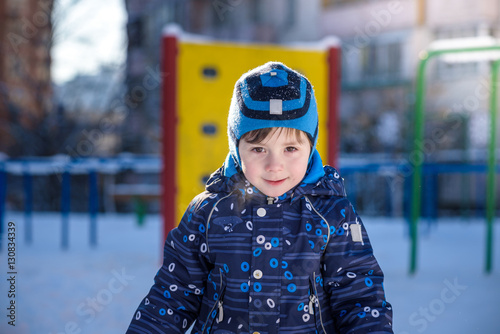 Funny little kid boy in colorful clothes playing outdoors during snowfall. Active leisure with children in winter on cold snowy days. Happy child having fun and snow © pahis