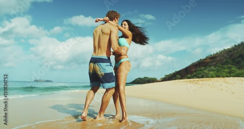 Attractive young couple kissing and playing on the beach on vacation
