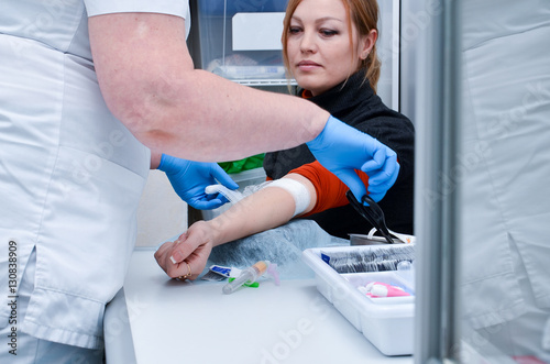 Preparation for blood test with pretty young blond woman by female doctor