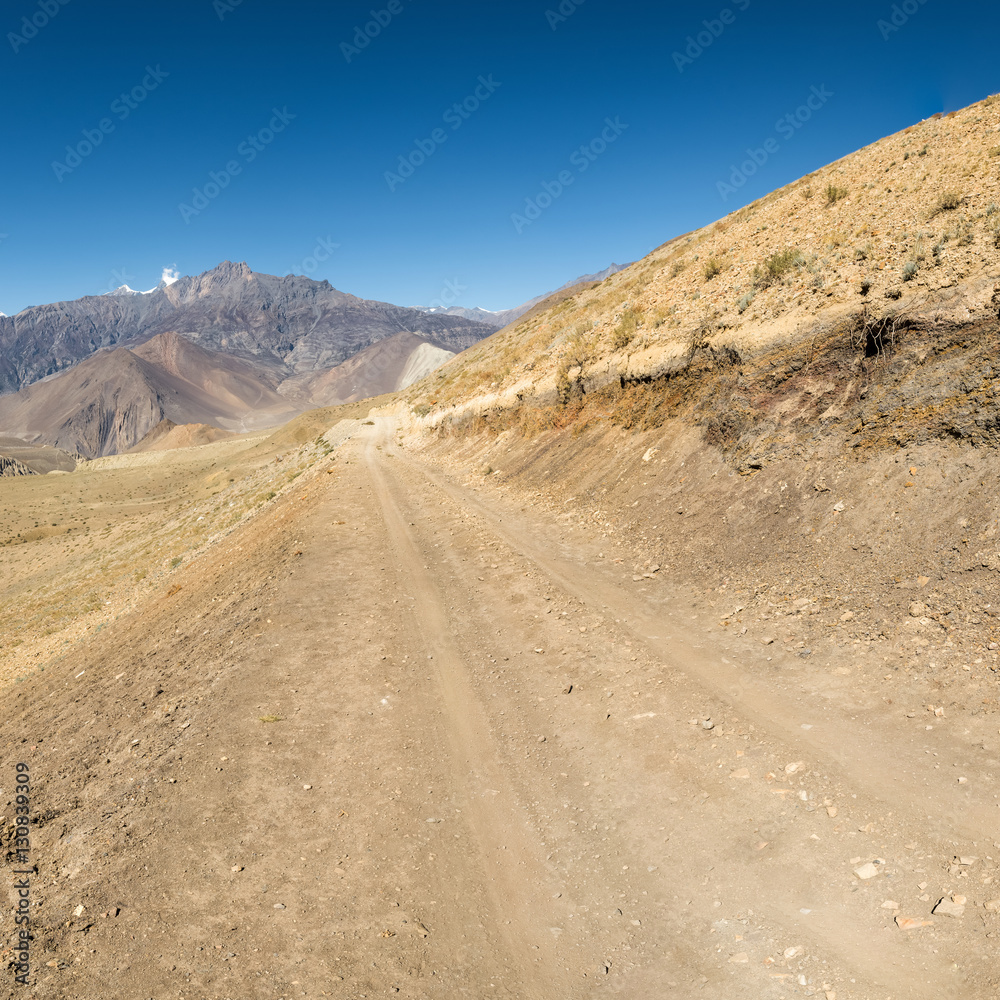 Dirt road through arid mountain wastelands. Dirt road through arid mountain wastelands.