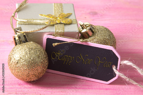 happy new year card with gift box and tag on pink wooden bakckground photo