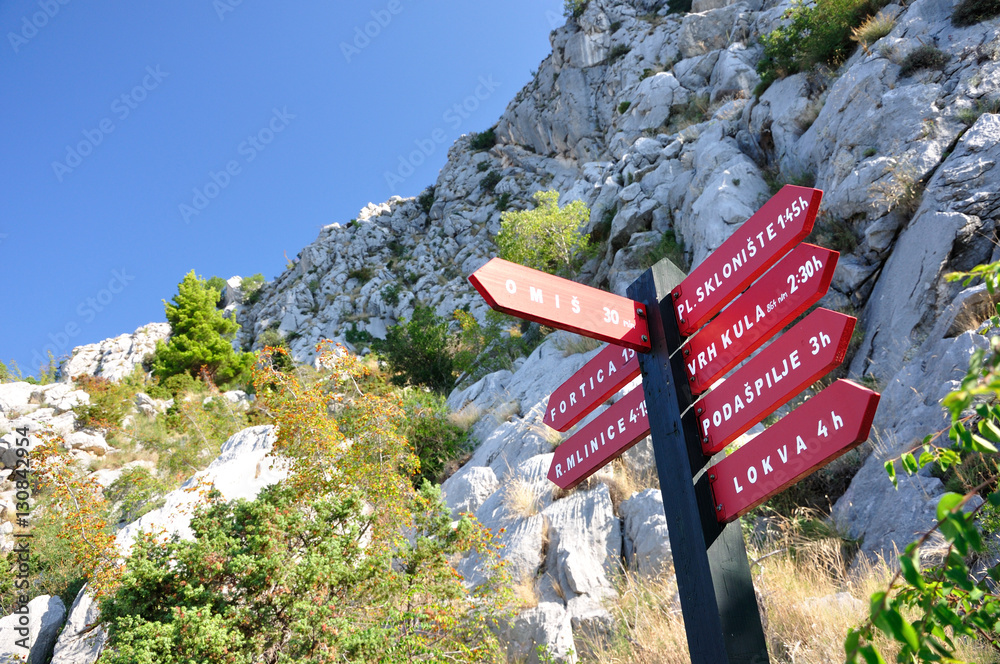 Słup z tablicami kierunkowymi szlaków turystycznych w Omisiu - Chorwacja - obrazy, fototapety, plakaty 