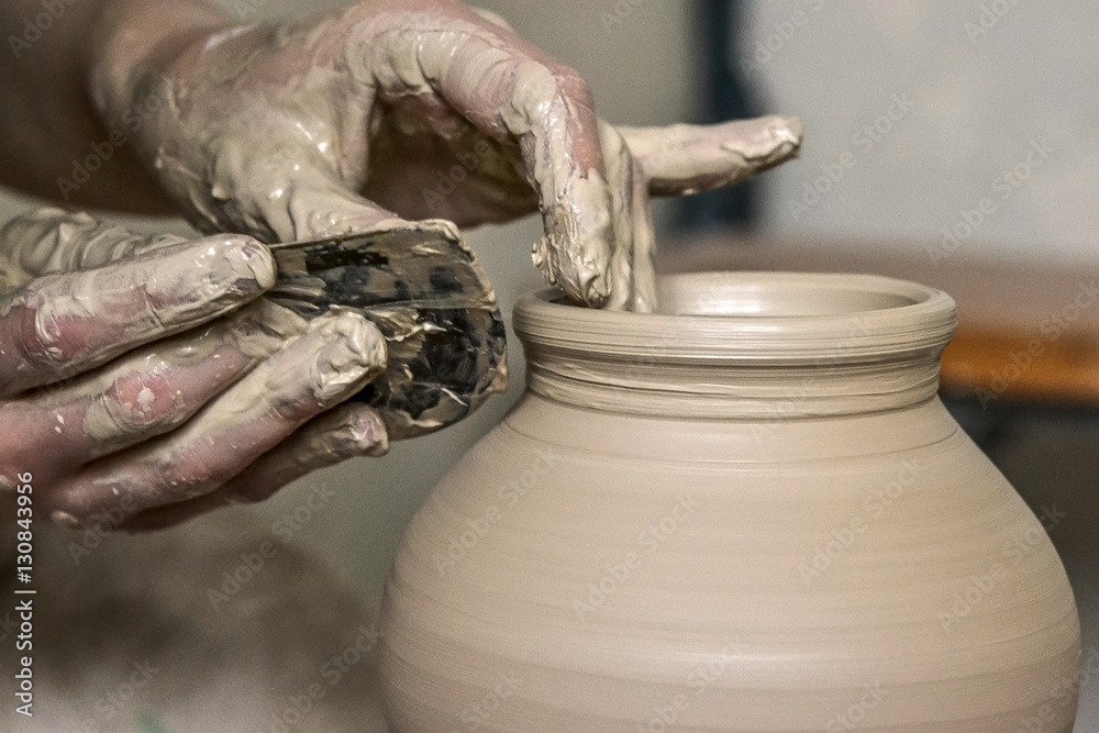 Making Crock crude wet close-up. Man hands and tool making clay jug macro. The sculptor in the workshop makes a jug out of clay closeup. Vase of white clay crude wet closeup,