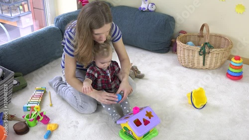young loving mom teaches daughter girl to distinguish object shapes.