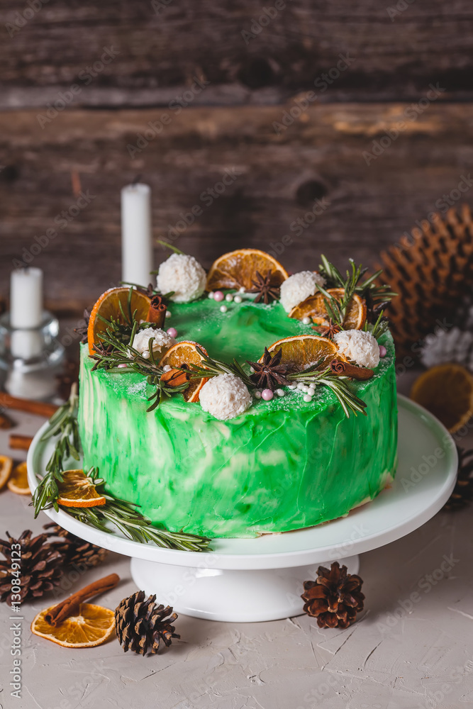 Green sponge cake on a wooden background. Decorated cones, candles, oranges cones, candles, oranges