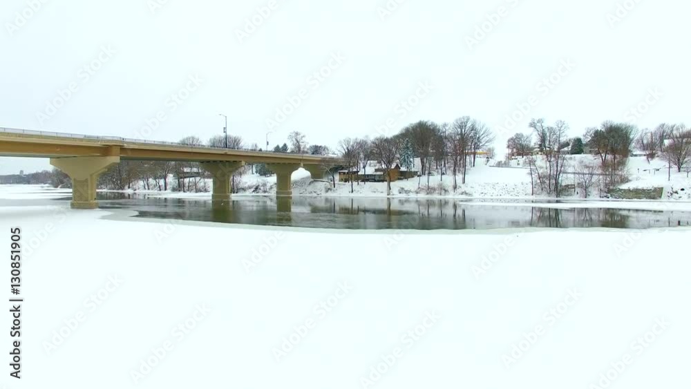 Scenic bridge over ice covered river in snow, aerial view.
Scenic bridge over ice covered river in snow, aerial view.