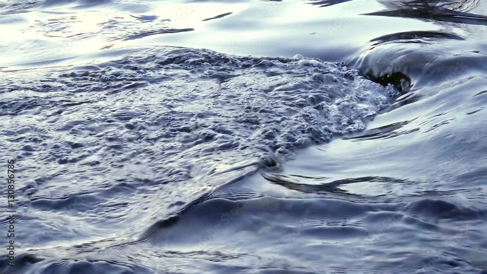 Flowing water in a blue river in slow motion