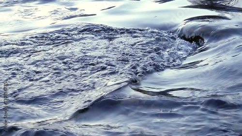 Flowing water in a blue river in slow motion
