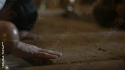 Close up of pilgrims hands at the Stone of Anointing in the Church of the Holy Sepulcher in Jerusalem.