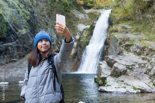 Fototapeta Naklejka Na Ścianę i Meble -  Woman taking selfie in forest with waterfalls