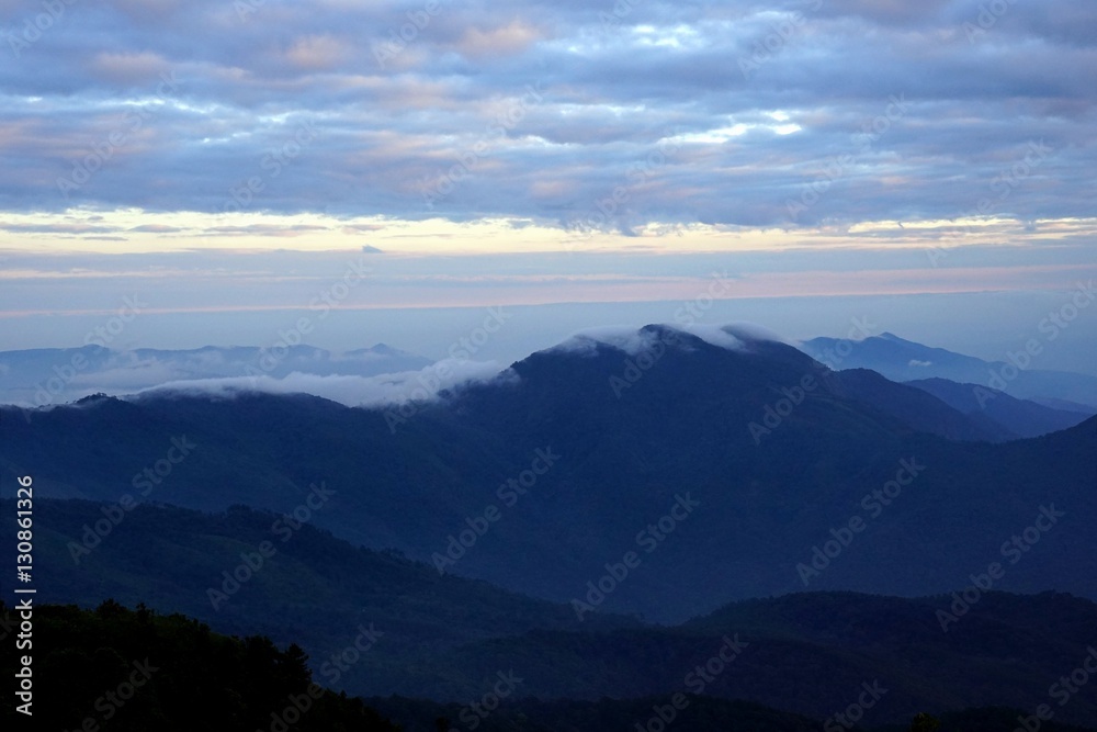 Mountain landscape with wave of fog and dark cloudy sky on the t