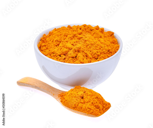 dry turmeric powder in white bowl and wooden spoon isolated on w