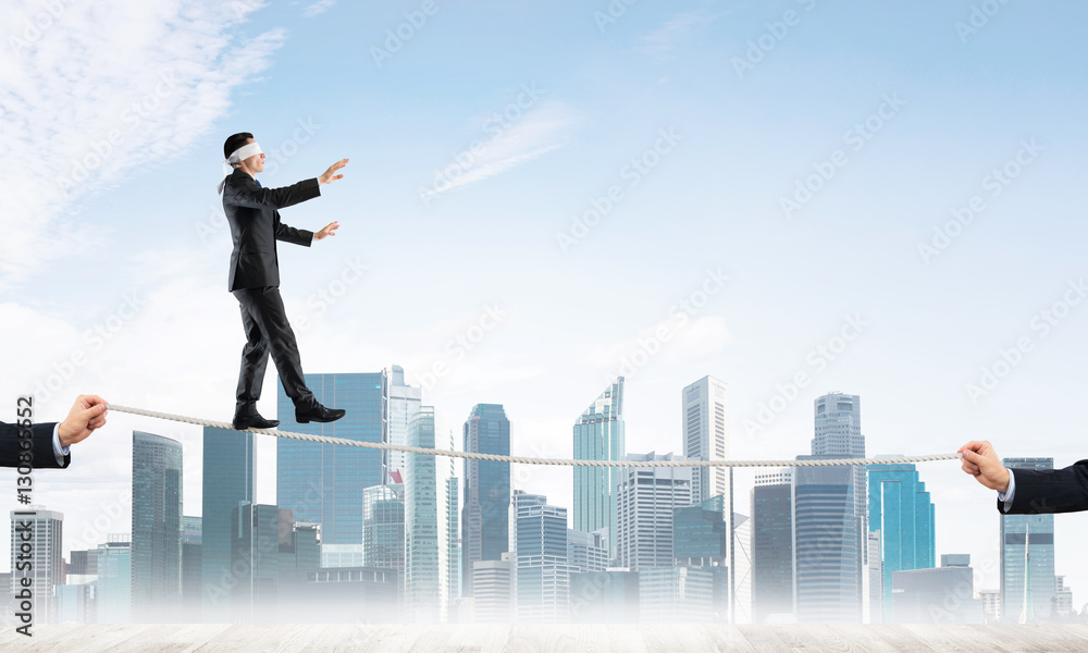 Business concept of risk support and assistance with man balancing on rope Business concept of risk support and assistance with man balancing on rope