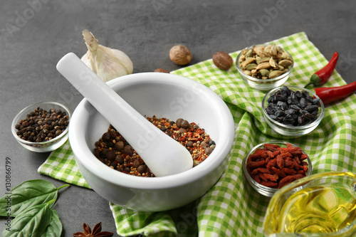 Composition with different spices and mortar on gray background