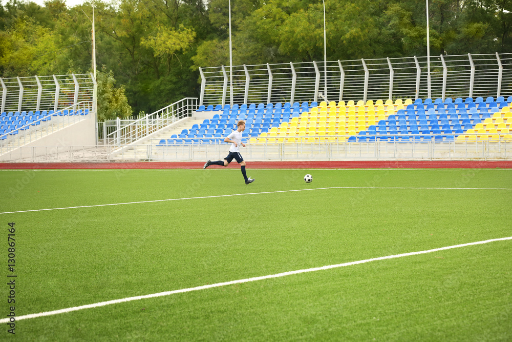 Fototapeta premium Boy playing football at stadium