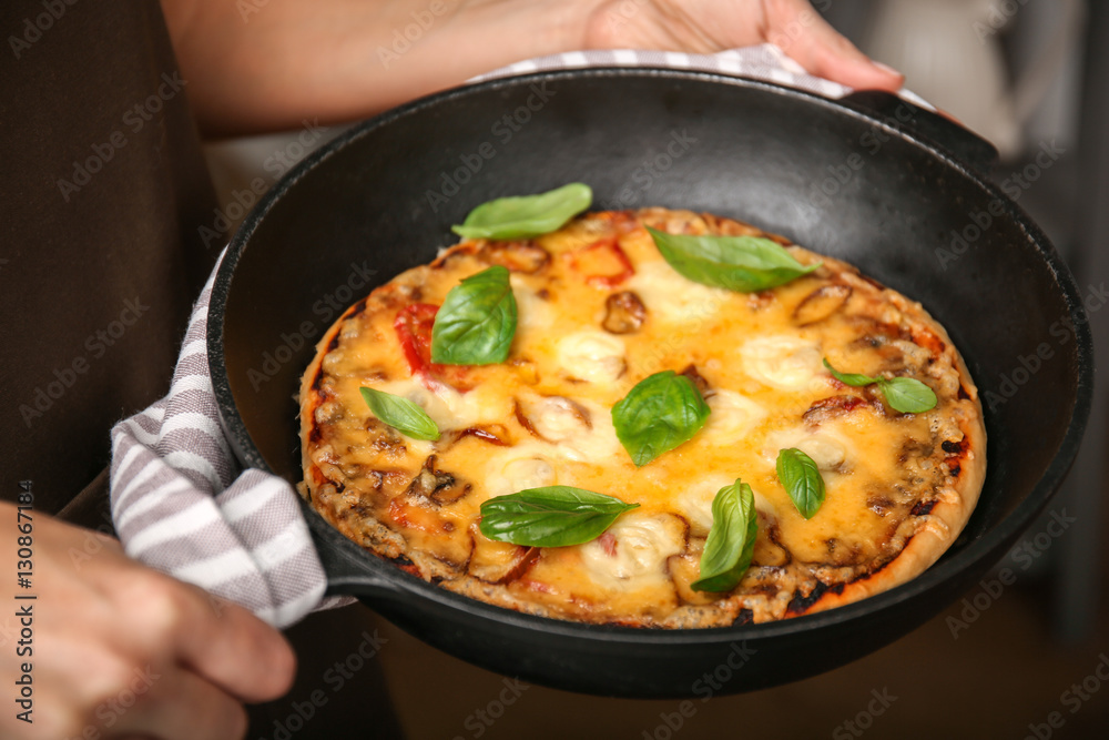 Woman holding freshly baked pizza in a pan