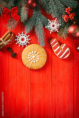 Composition of tasty gingerbread cookies and Christmas decor on red wooden background
