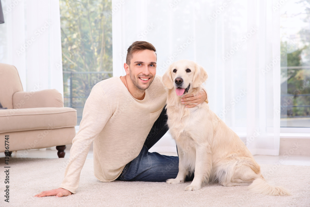 Handsome man with dog sitting on carpet at home