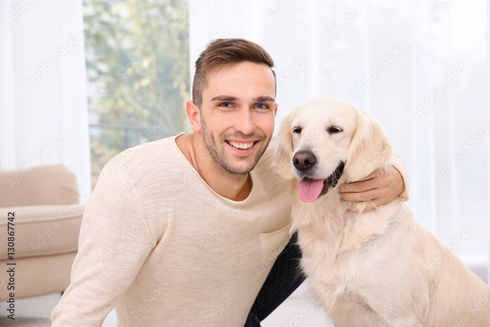 Portrait of handsome man with dog sitting at home
