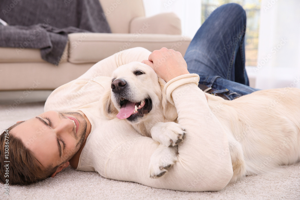 Handsome man with dog lying on carpet at modern room interior Handsome man with dog lying on carpet at modern room interior