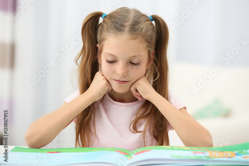 Cute girl reading book at home