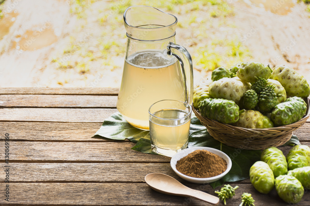 Noni fruit and noni juice with noni powder and wooden spoon on wooden table.Fruit for health and herb for health Stock Photo | Adobe Stock