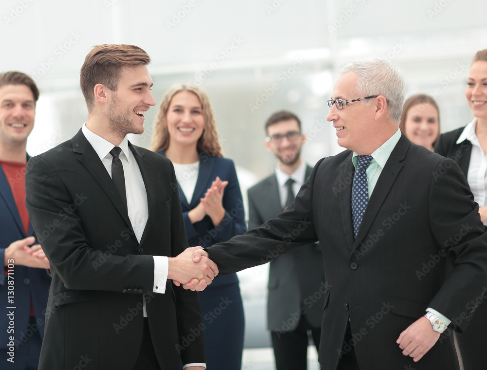 Two cheerful business people shaking hands while their colleague Two cheerful business people shaking hands while their colleague