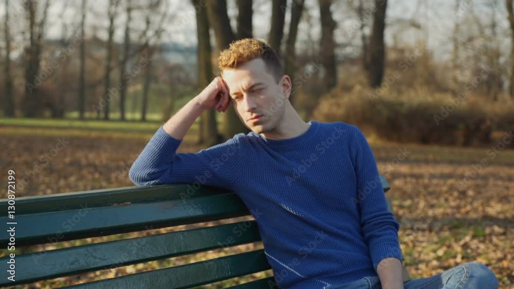 Handsome man sitting in the park and looking thoughtful, steadycam shot
Handsome man sitting in the park and looking thoughtful, steadycam shot