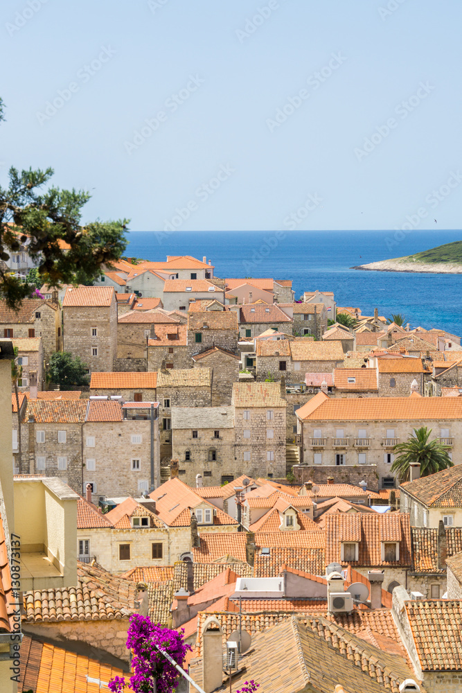 Overlooking a typical vista of the old town in Hvar Town, Croatia, with the orange terracotta rooftops and the azure Adriatic Sea.