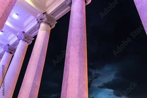 Purple iluminated columns next to rainy clouds photo