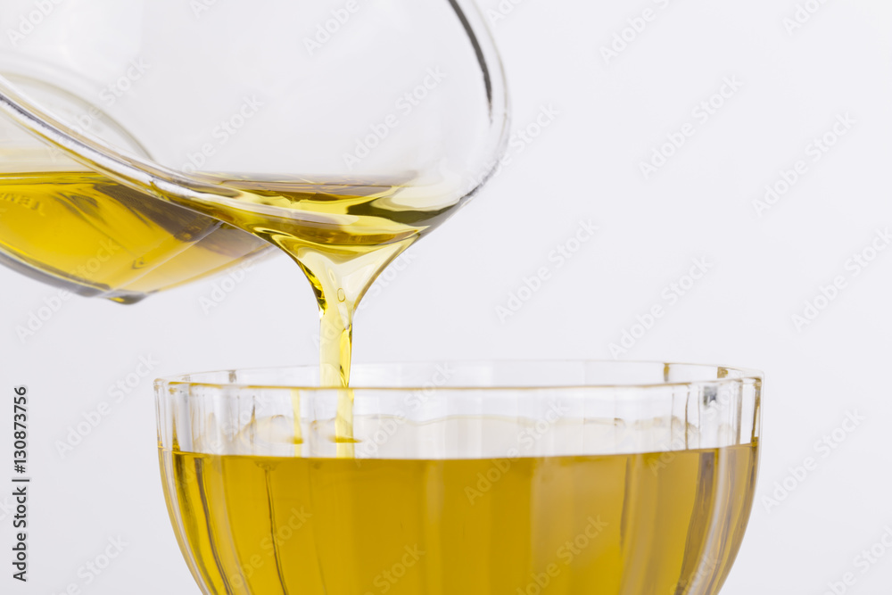 Olive oil flows from a glass bowl