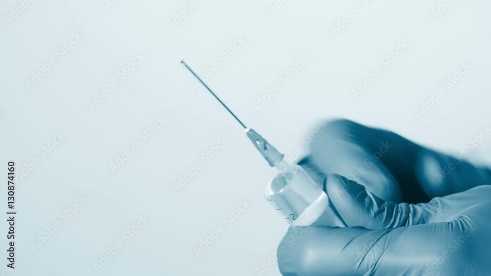 Doctor in gloves and uniform prepares syringe for giving injection