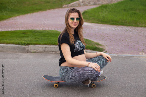 Pregnant woman sitting on the skateboard 