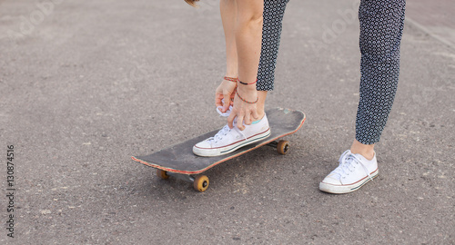 Woman on the skateboard tying shoelaces