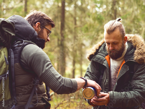 Man with a beard and his friend hiking in a forest © Acronym