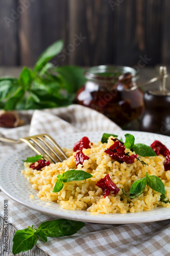 Bulgur with dried tomatoes and basil on an old wooden background. Vegetarian dish.Rustic style. Selective focus.
