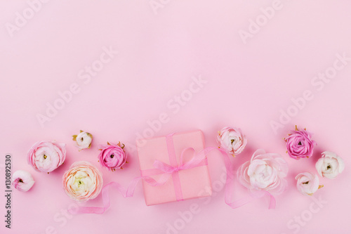 Gift or present box and beautiful spring flower on pink desk from above for wedding mockup or greeting card on womans day in flat lay style.