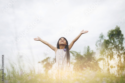 Cute Asian Girl raised hand at meadow  happily.