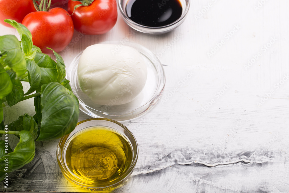Ingredients for cooking italian capreze salad cherry tomatoes, basil leaves, mozzarella cheese, spices and olive oil on wooden rustic background top view close up Ingredients for cooking italian capreze salad cherry tomatoes, basil leaves, mozzarella cheese, spices and olive oil on wooden rustic background top view close up