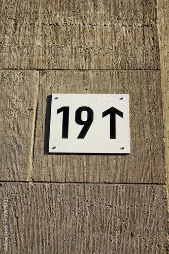 Modern building number with arrow showing up on stone wall in Berlin