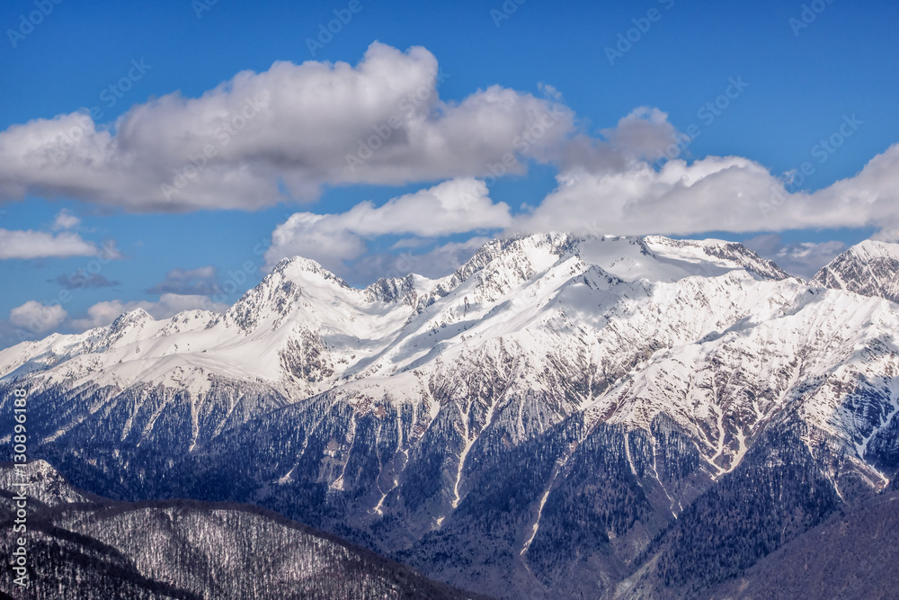 Beautiful snowy mountain peaks and blue sky with clouds scenic winter landscape of the Main Caucasus ridge